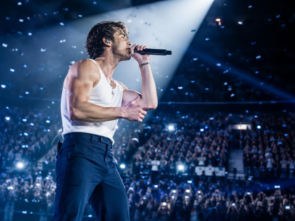 Artista cantando no palco durante show com grande público